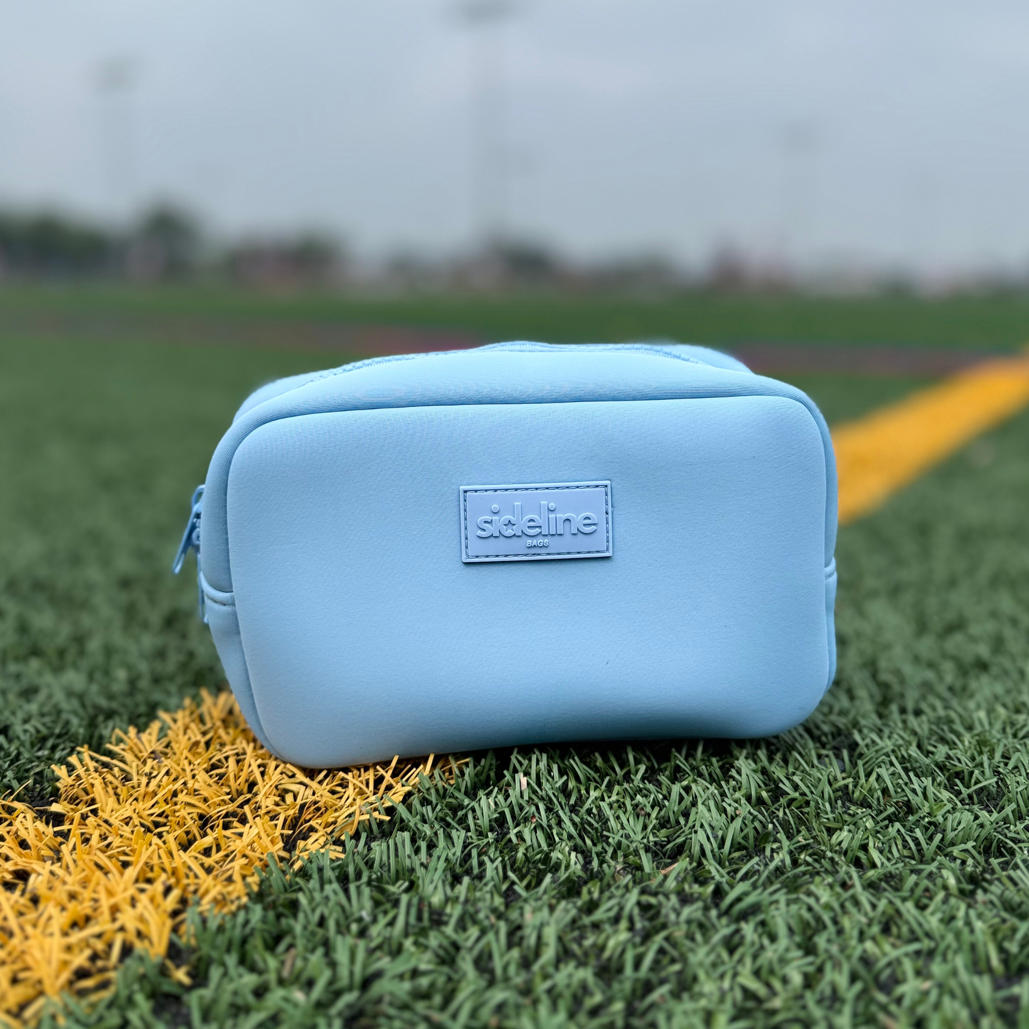 Carolina blue travel organizer pouch out on the field from Sideline Bags.