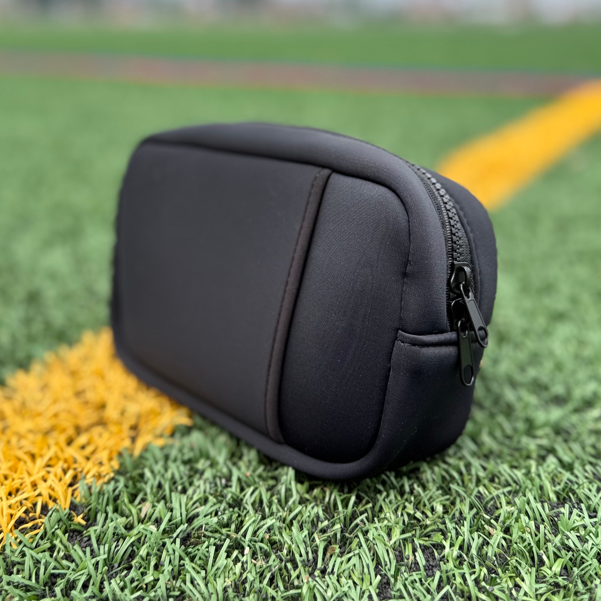 Black travel organizer pouch out on the field by Sideline Bags.
