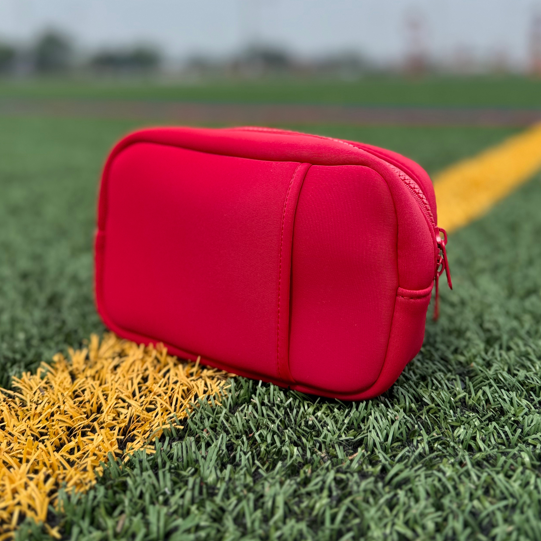 Red travel organizer pouch on the field from Sideline Bags.